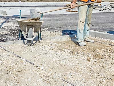 TX Mulching and Dozer Images - Construction worker shoveling stone garage pad